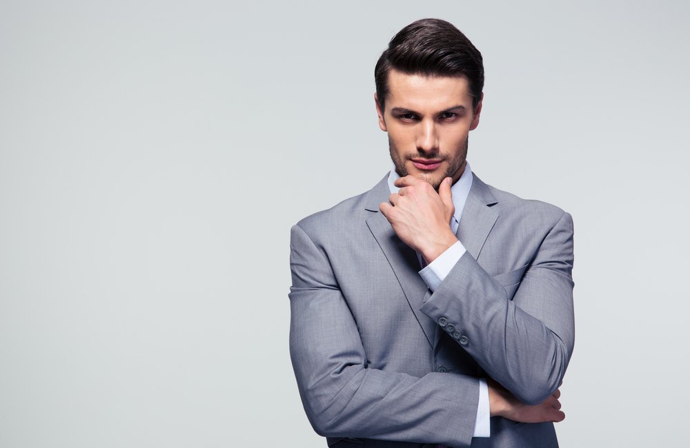 Portrait-of-a-pensive-businessman-touching-his-chin-over-gray-background